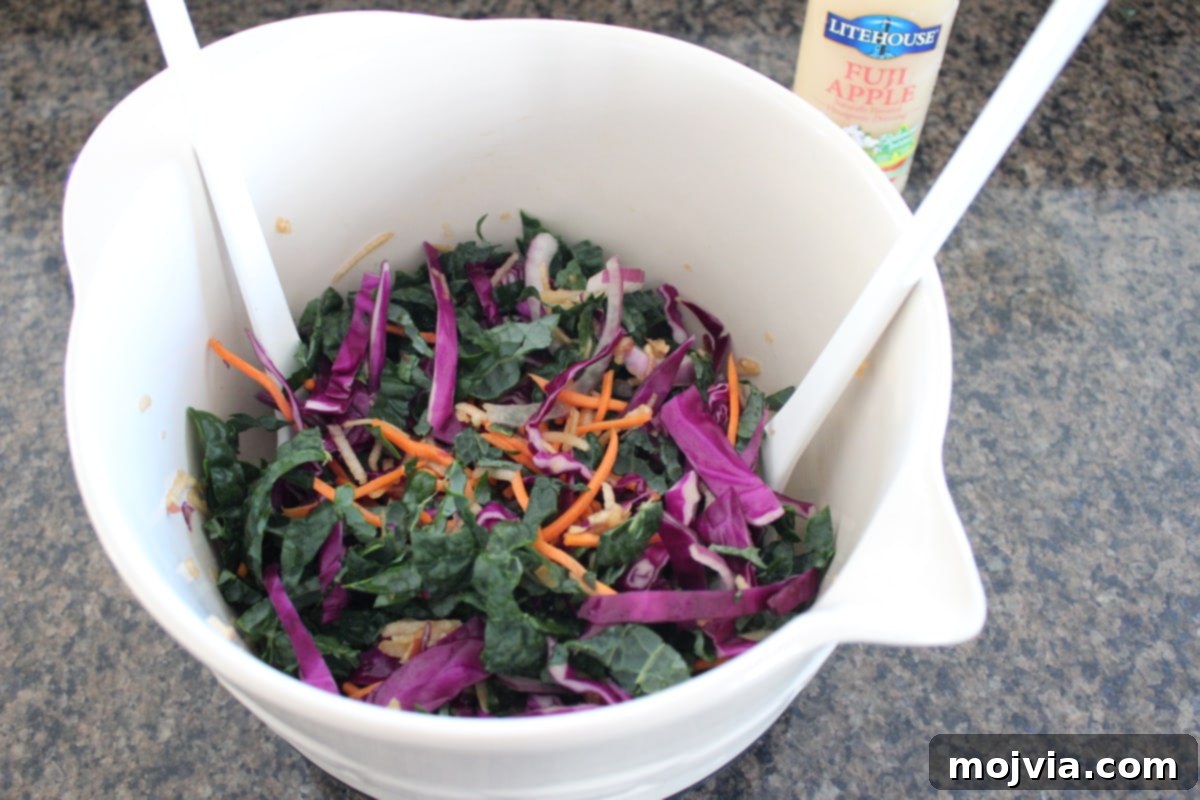 Crisp Kale and Apple Slaw 4 Kale Apple Slaw being tossed in a large mixing bowl, showing the vibrant colors of the ingredients.