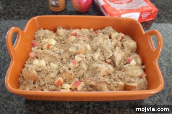 unbaked bread pudding in baking dish topped with diced apples and brown sugar crumble