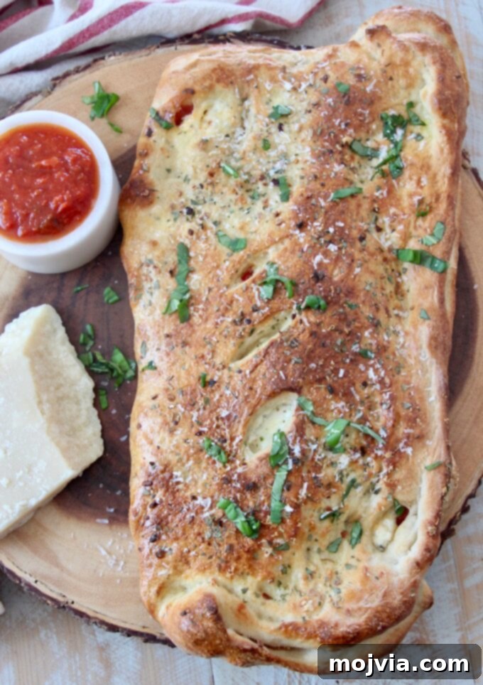 A freshly baked, golden-brown calzone placed on a rustic wooden serving board, ready to be sliced and enjoyed.