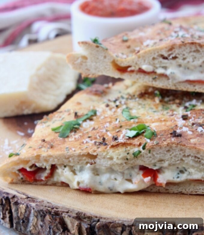 A large, homemade calzone sliced open on a wooden cutting board, showcasing its melted cheese, pepperoni, and vegetable filling, ready for serving.