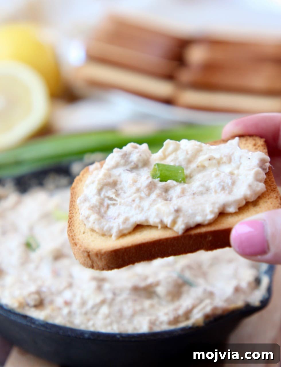 Baked Crab Dip 4 Hand holding brioche toast, topped with hot crab dip, ready to eat
