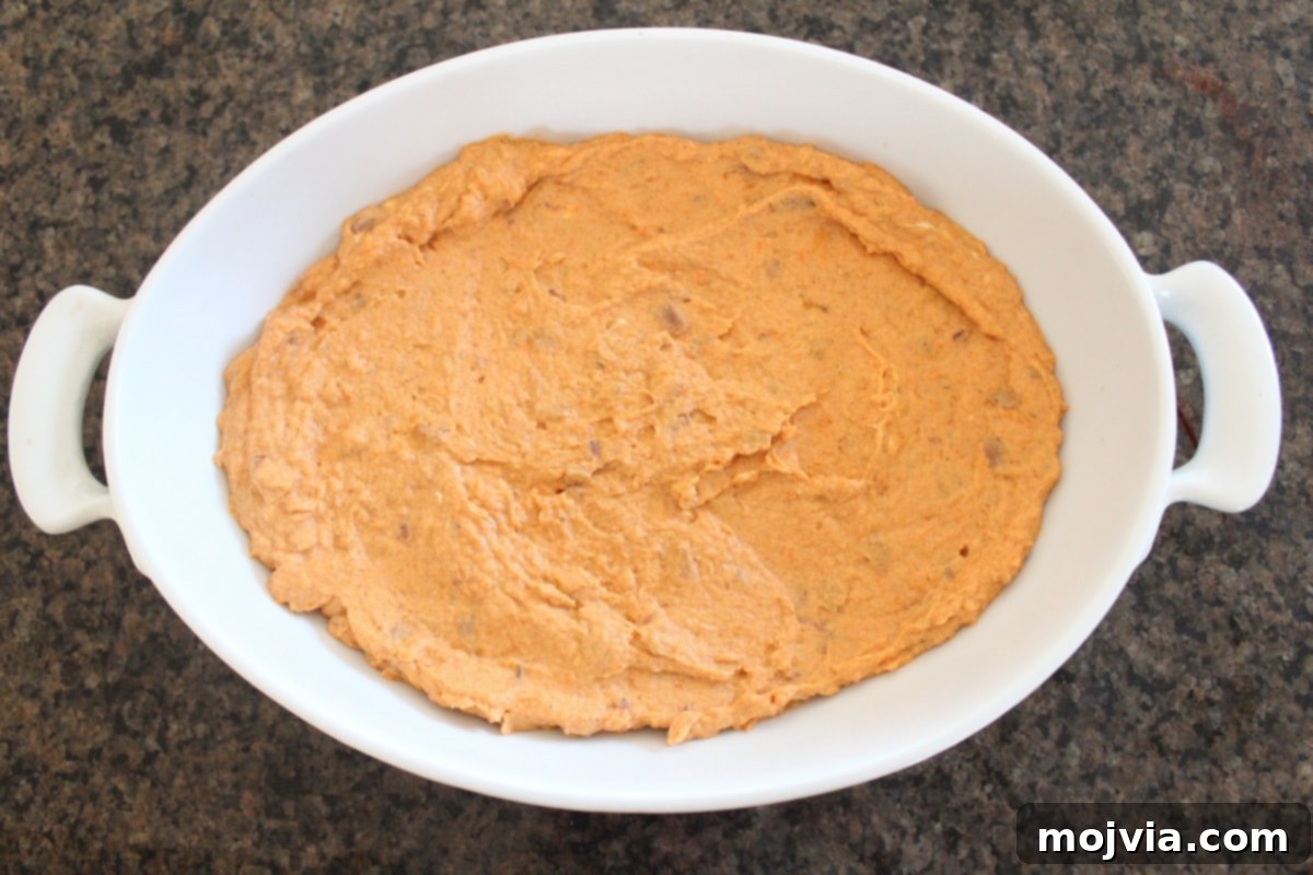 Sweet potato and three cheese dip placed in a small baking dish, ready for goat cheese topping.