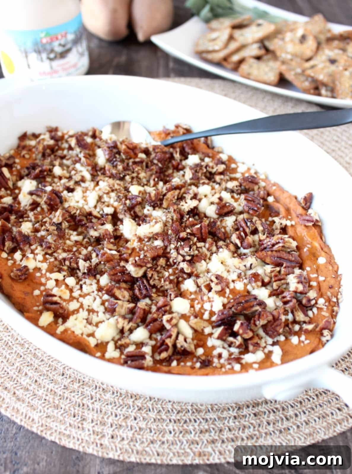 Creamy Baked Sweet Potato Dip Recipe, fresh from the oven, topped with candied pecans and drizzled with maple syrup.