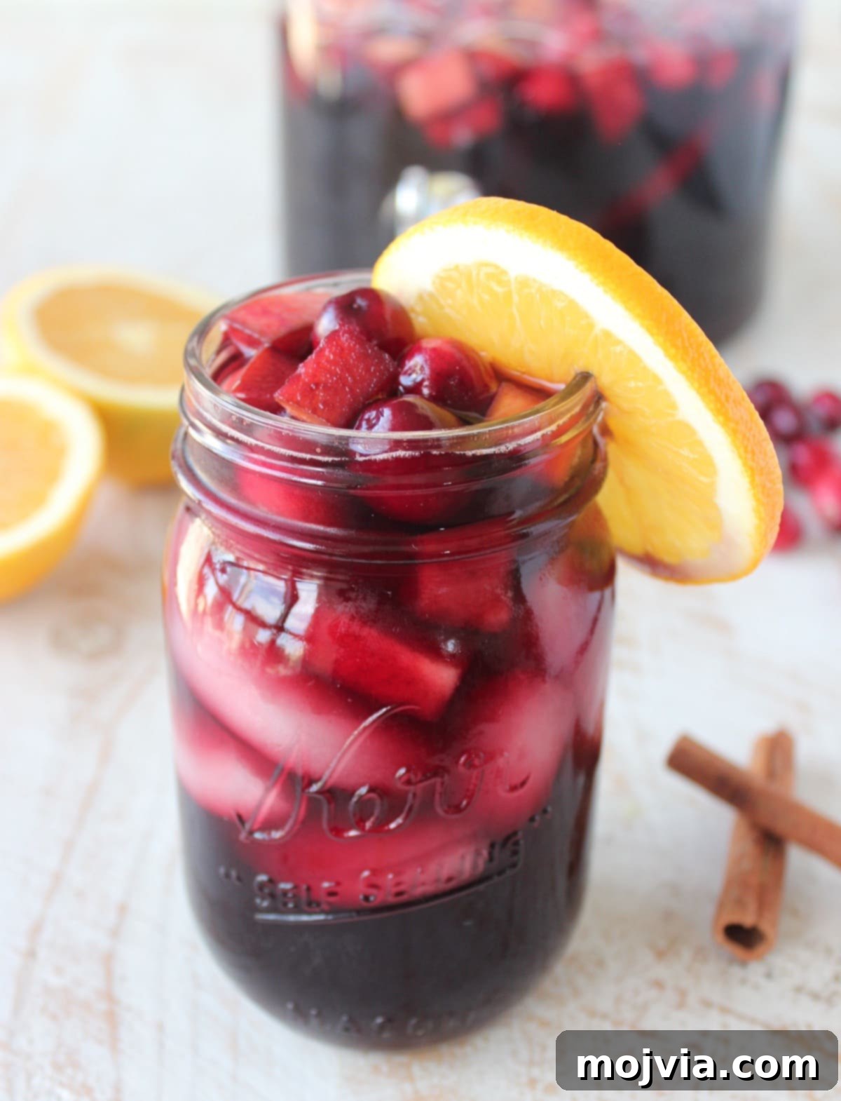 Cranberry Apple Sangria in a mason jar with an orange slice on the rim of the glass