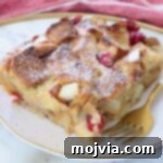 A slice of French toast casserole on a plate with a fork, ready to be eaten.