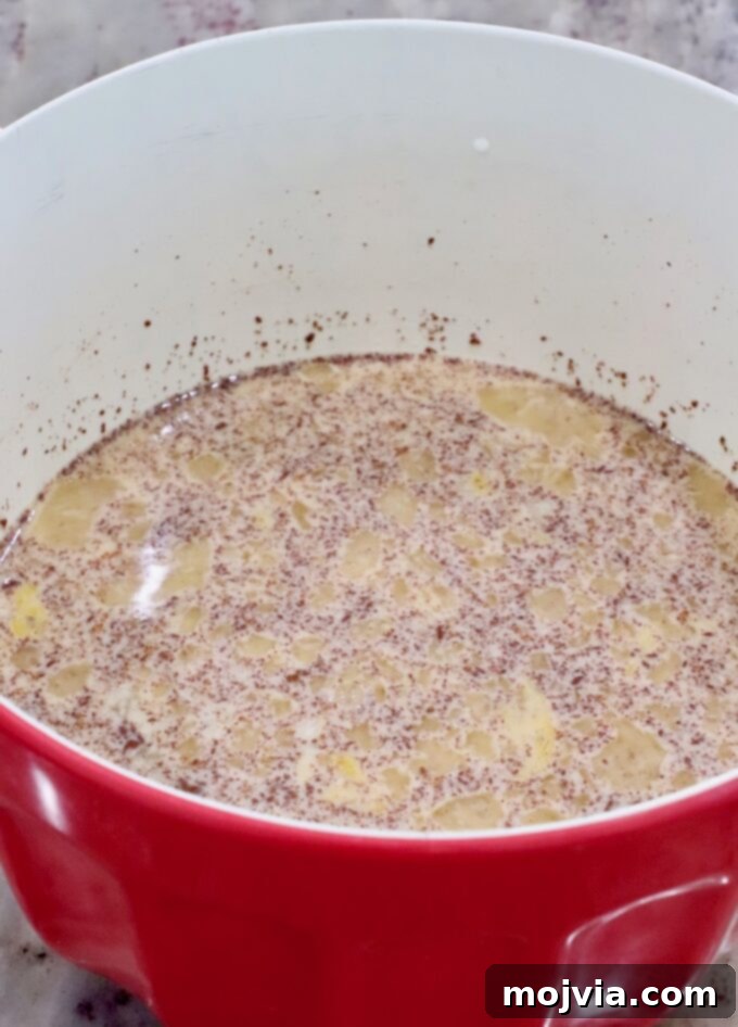 Milk, eggs, and cinnamon being whisked together in a large mixing bowl to create the rich custard mixture for the French toast bake.