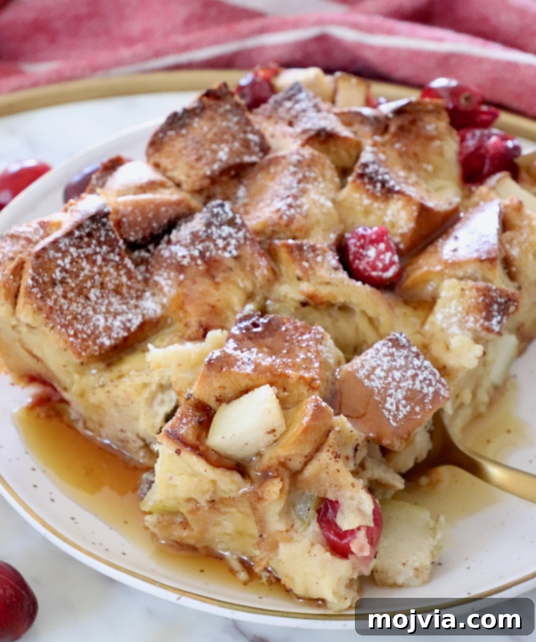 A single piece of golden French toast bake on a white plate with a fork, drizzled with maple syrup, highlighting its delicious texture.