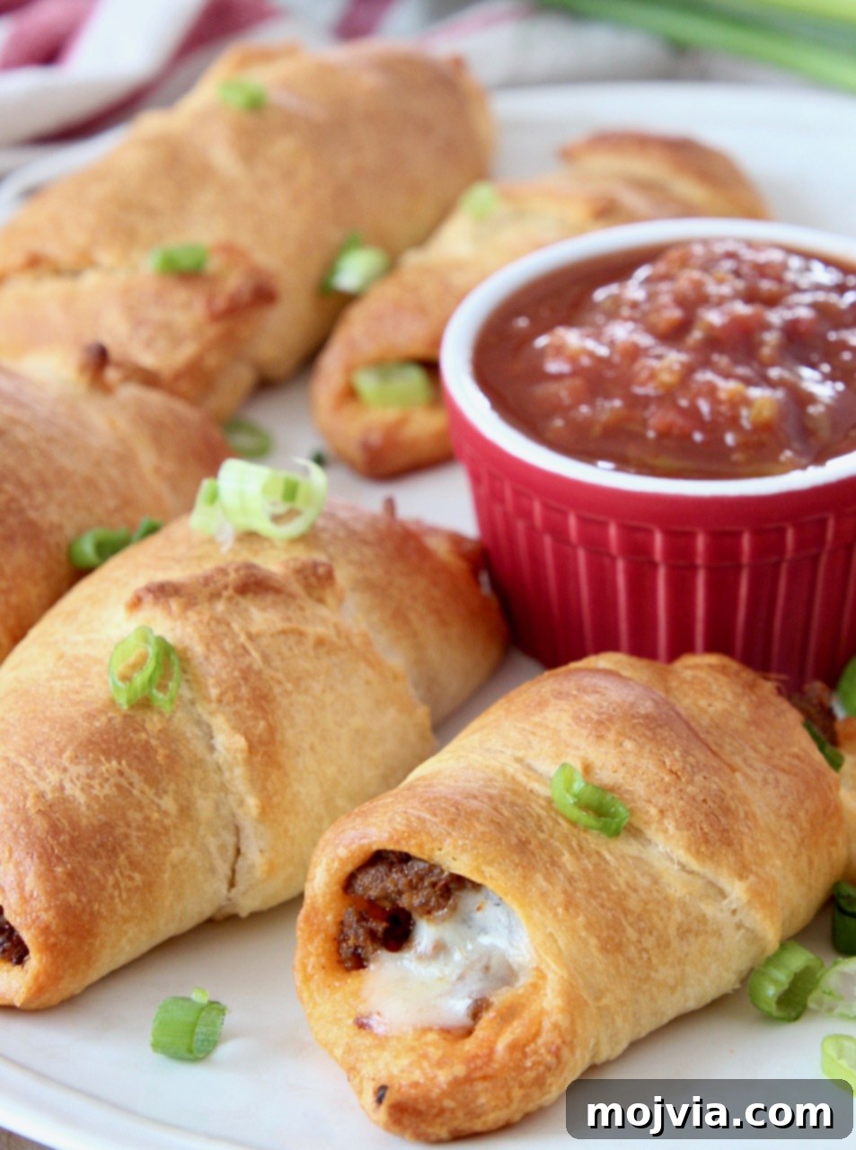 Taco Roll-Up Bites 2 taco crescent rolls on plate with small bowl of salsa