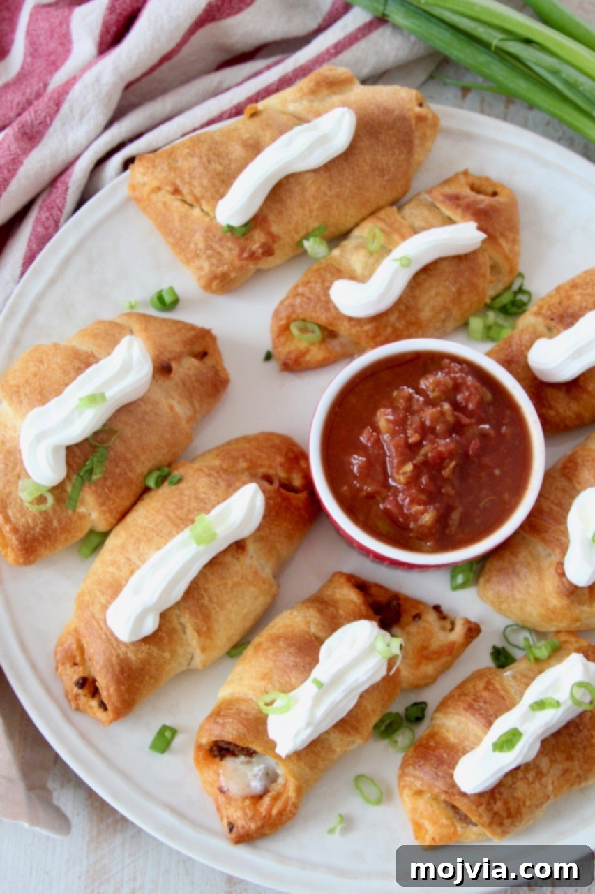 Taco Roll-Up Bites 5 baked taco croissants on plate topped with sour cream