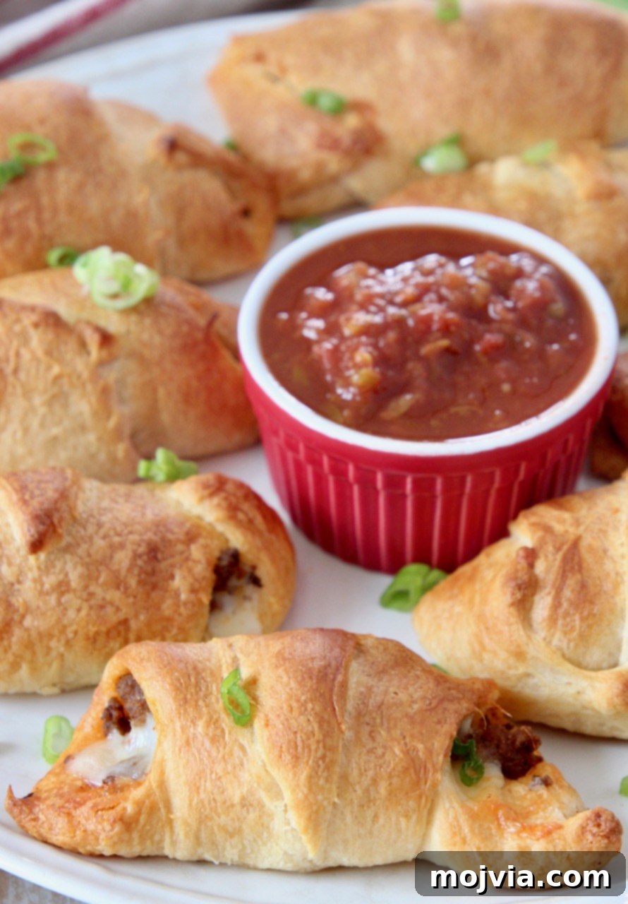 Taco Roll-Up Bites 6 cooked taco filled crescent rolls on plate with bowl of salsa