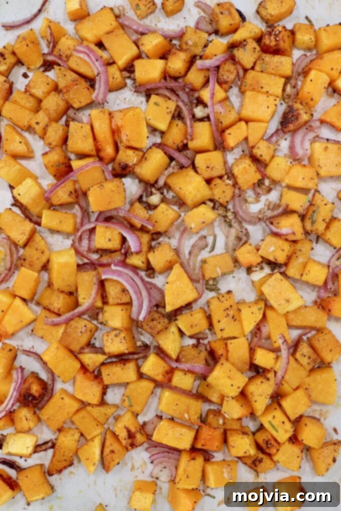 Golden Roasted Butternut Salad 5 roasted cubed butternut squash with sliced onions and minced garlic on a parchment paper lined baking sheet