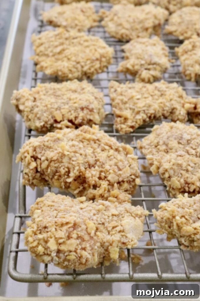 Sweet Heat Chipotle Chicken Tenders 11 Uncooked, breaded chicken pieces arranged on a wire rack over a baking sheet.