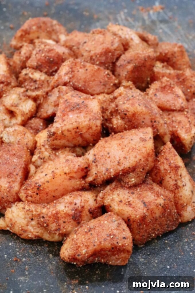Sweet Heat Chipotle Chicken Tenders 7 Raw chicken cubes on a cutting board, thoroughly seasoned with spices.