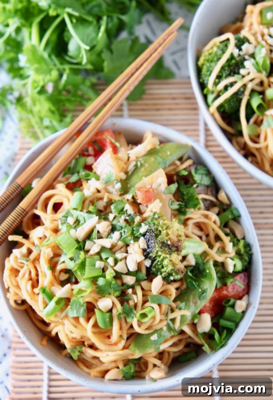 Creamy Thai Peanut Noodles with Fresh Vegetables 2 A bowl of Thai Peanut Noodles with fresh vegetables, topped with chopped peanuts and green onions. Chopsticks rest on the side of the bowl, ready for enjoyment.