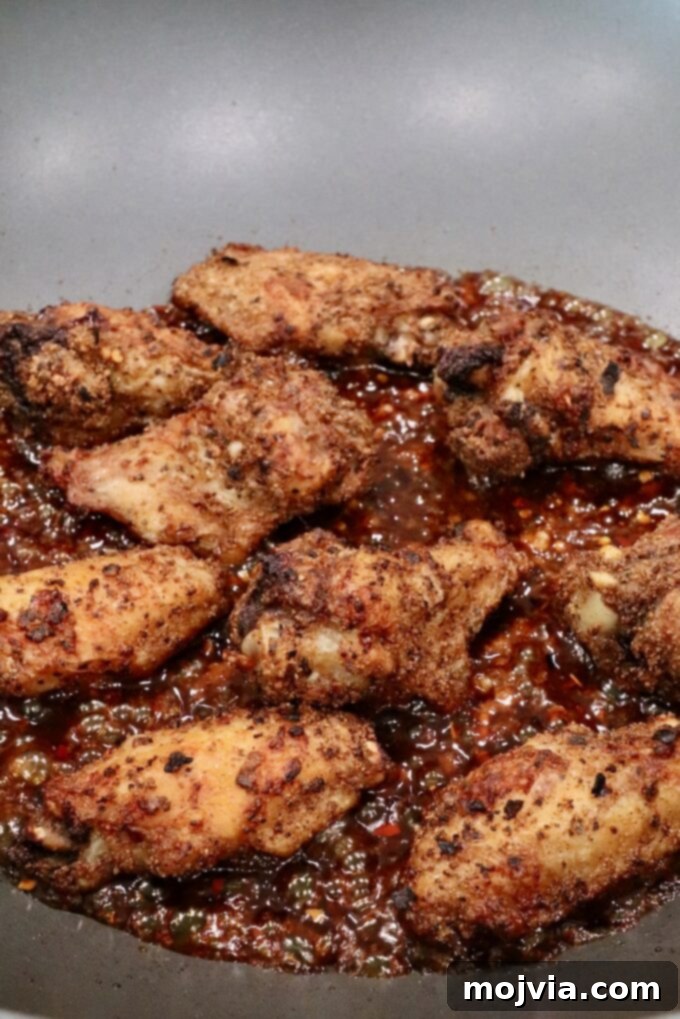 cooked chicken wings in a wok with sauce