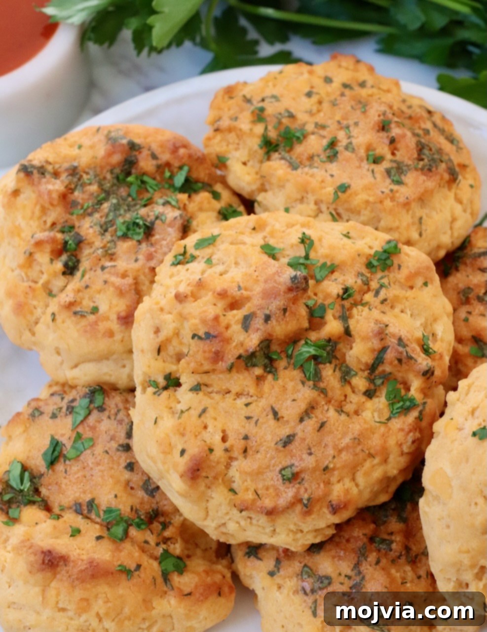 Buffalo Cheddar Zingers 2 cheddar biscuits stacked up on a plate topped with fresh chopped parsley