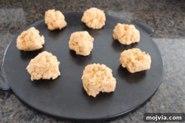 Buffalo Cheddar Zingers 5 biscuit dough dolloped on a black round baking stone