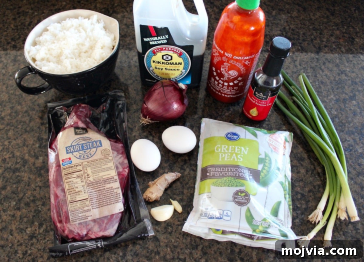 Spicy Sriracha Steak Fried Rice 3 Fresh ingredients for Sriracha Steak Fried Rice, including onions, peas, garlic, eggs, skirt steak, soy sauce, ginger, and Sriracha.