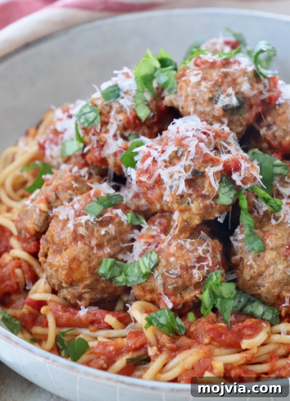 Set-and-Forget Slow Cooker Meatballs and Marinara 2 cooked meatballs in bowl with tomato sauce and cooked spaghetti noodles