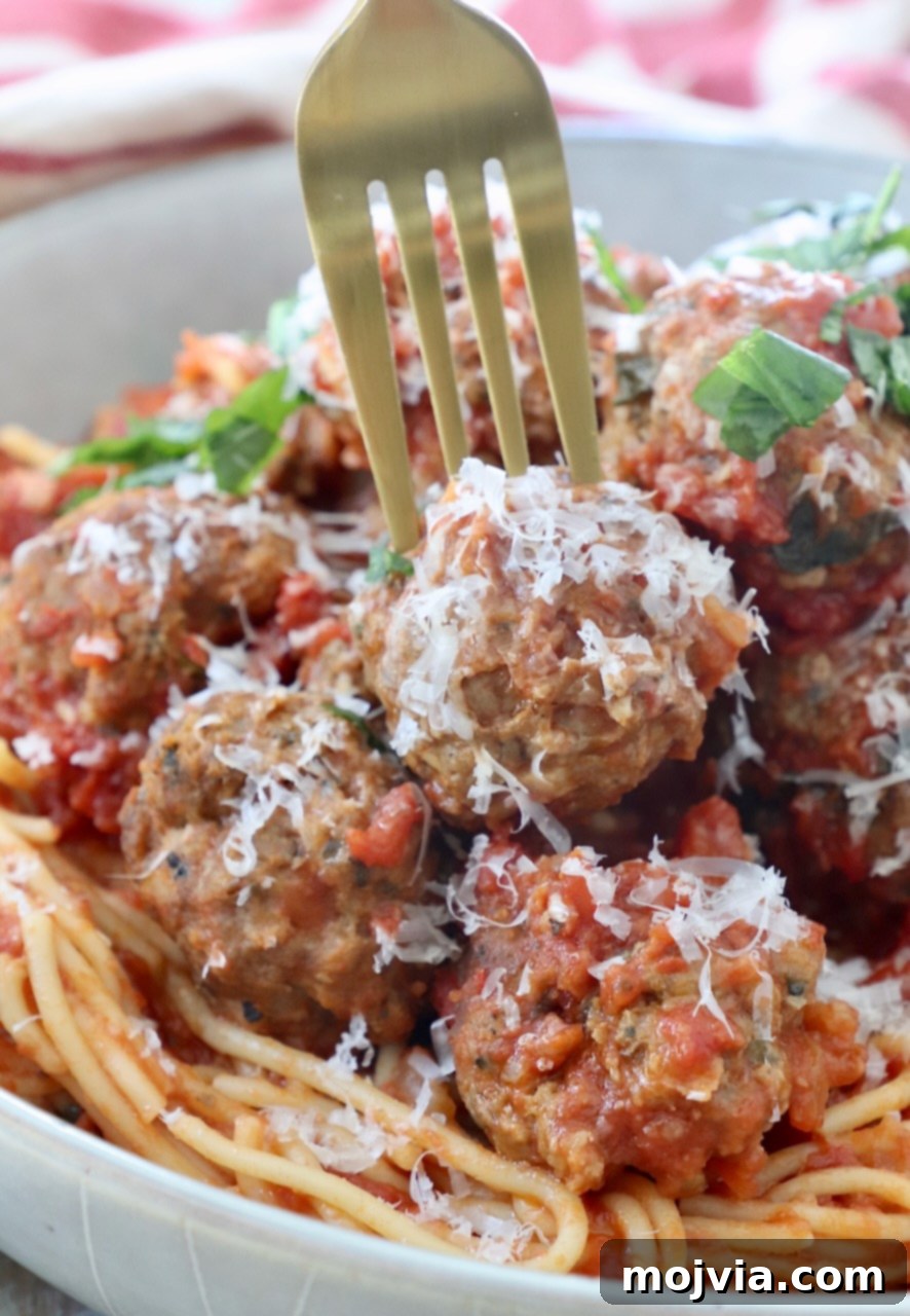 Set-and-Forget Slow Cooker Meatballs and Marinara 12 fork picking up meatball from bowl of spaghetti and meatballs