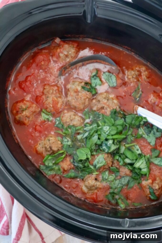 Set-and-Forget Slow Cooker Meatballs and Marinara 10 meatballs in slow cooker with tomato sauce, fresh basil and serving spoon