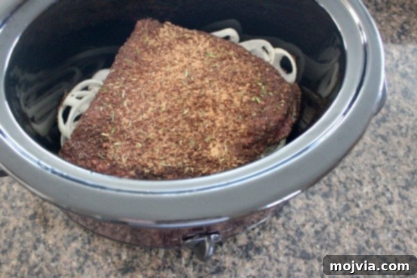 Brisket coated in coffee rub placed on onions in slow cooker