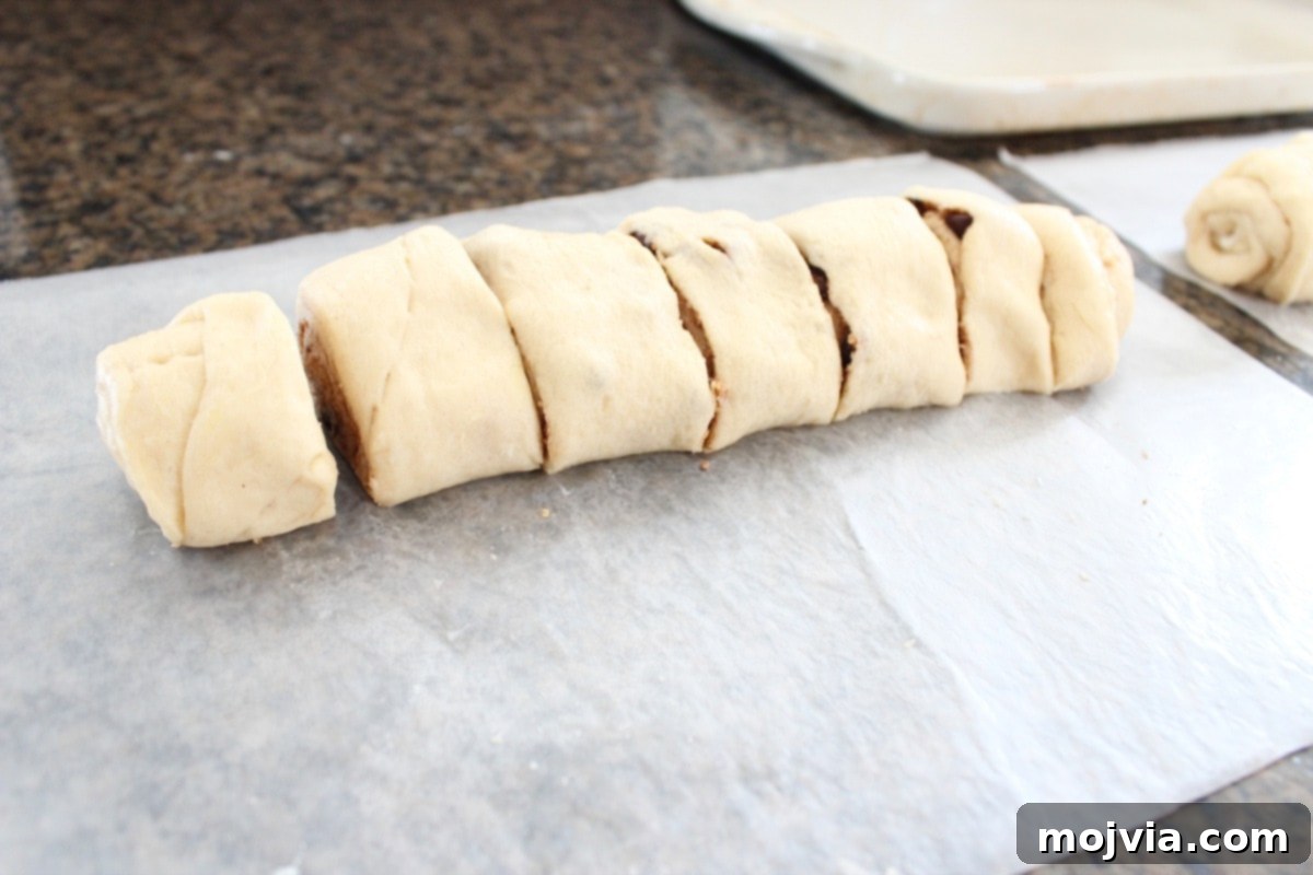 Slicing the rolled dough into individual S'Mores Cinnamon Rolls.