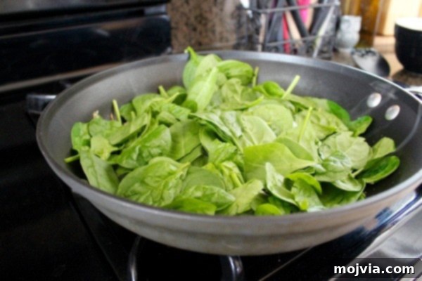 Gourmet Spinach Artichoke Turkey Burgers 4 Fresh spinach wilting in a large skillet