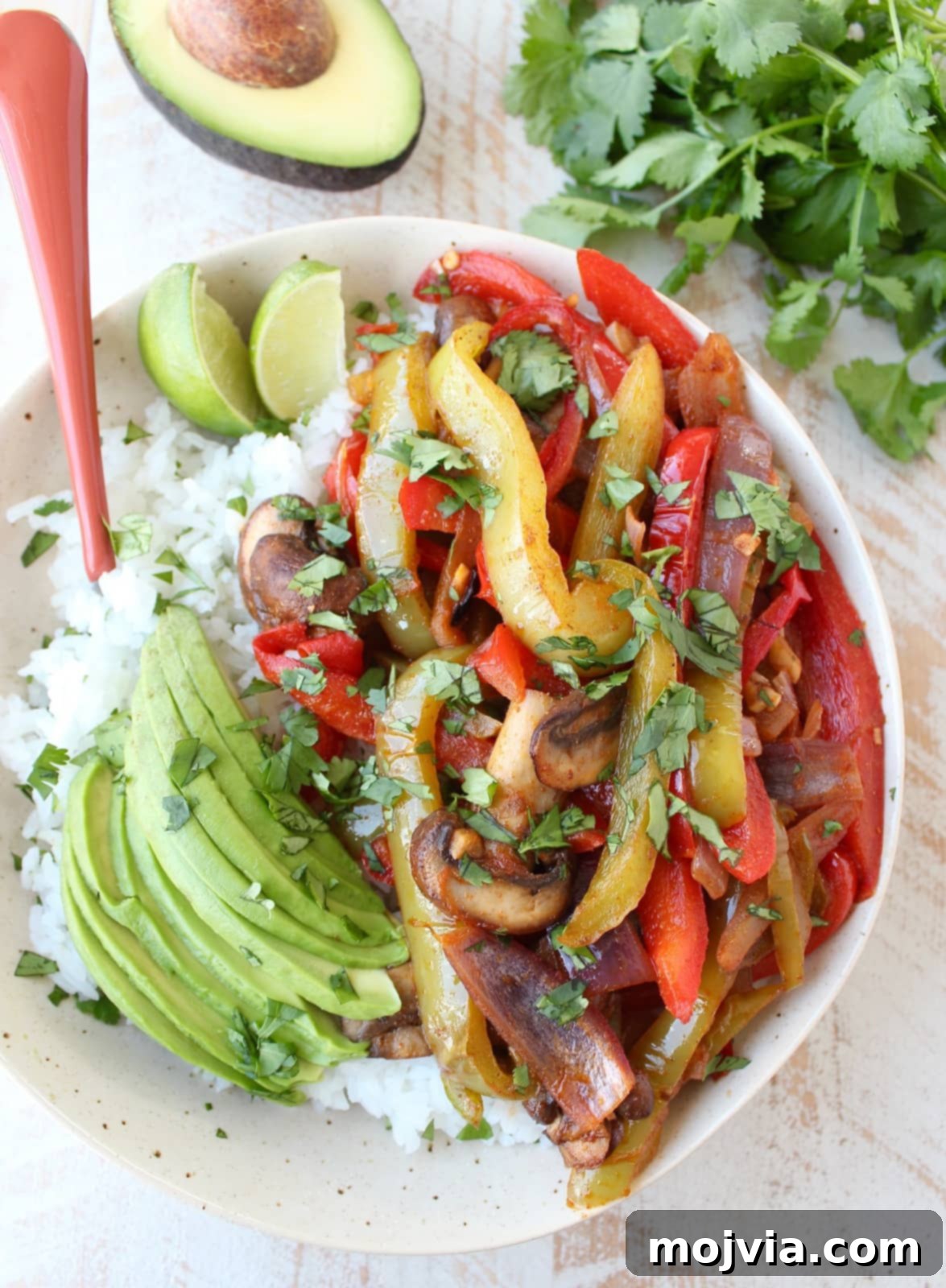 Vibrant Veggie Fajita Rice Bowl 2 Flavorful Veggie Fajita Rice Bowl with bell peppers, onions, mushrooms, cilantro lime rice, and sliced avocado