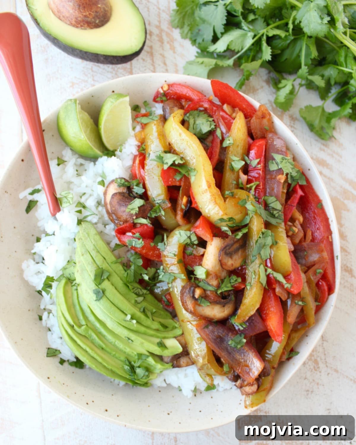 Vibrant Veggie Fajita Rice Bowl 4 Veggie fajitas and sliced avocado on top of cooked white rice in a bowl