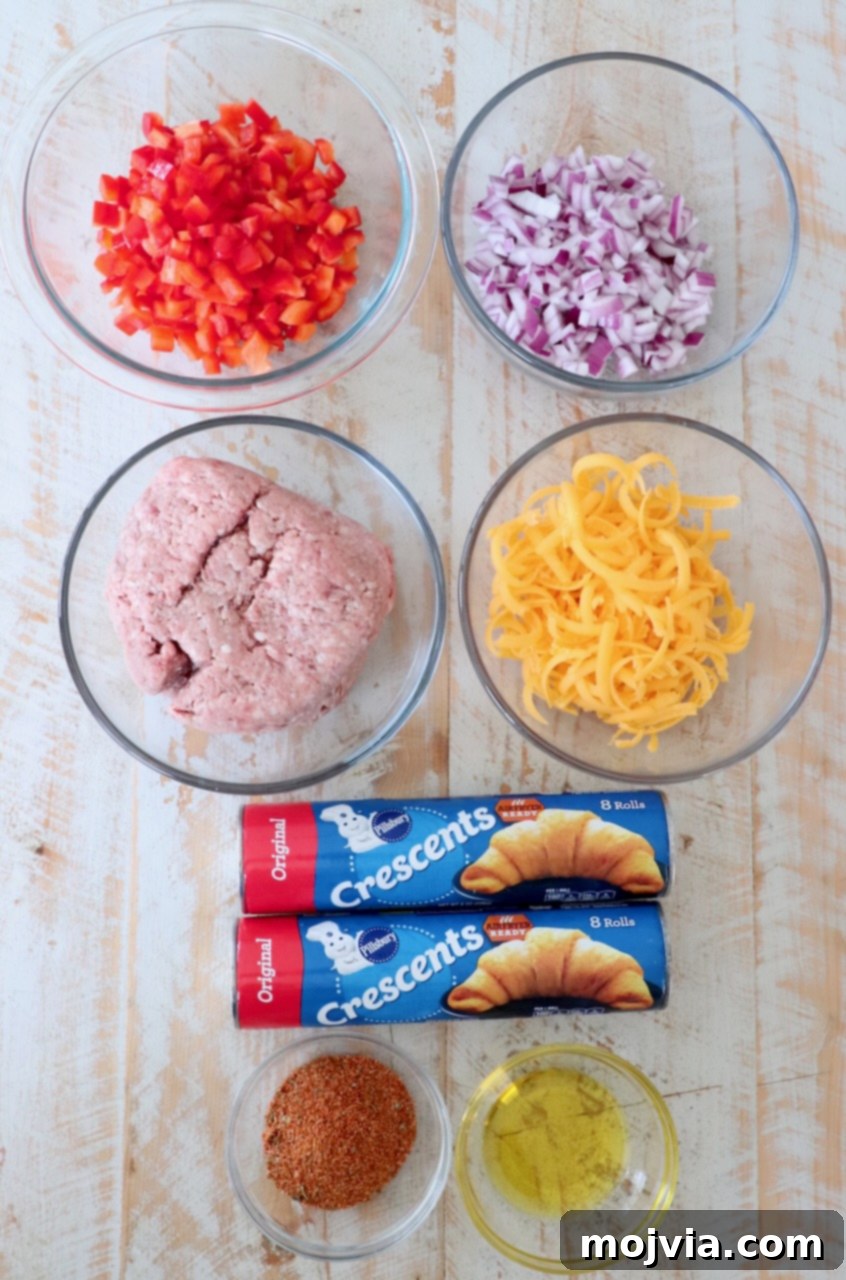 Fiesta Taco Ring 3 A selection of fresh ingredients including Pillsbury crescent rolls, ground beef, bell peppers, onions, cheddar cheese, and taco seasoning, arranged on a white wooden board, ready for making a taco ring.