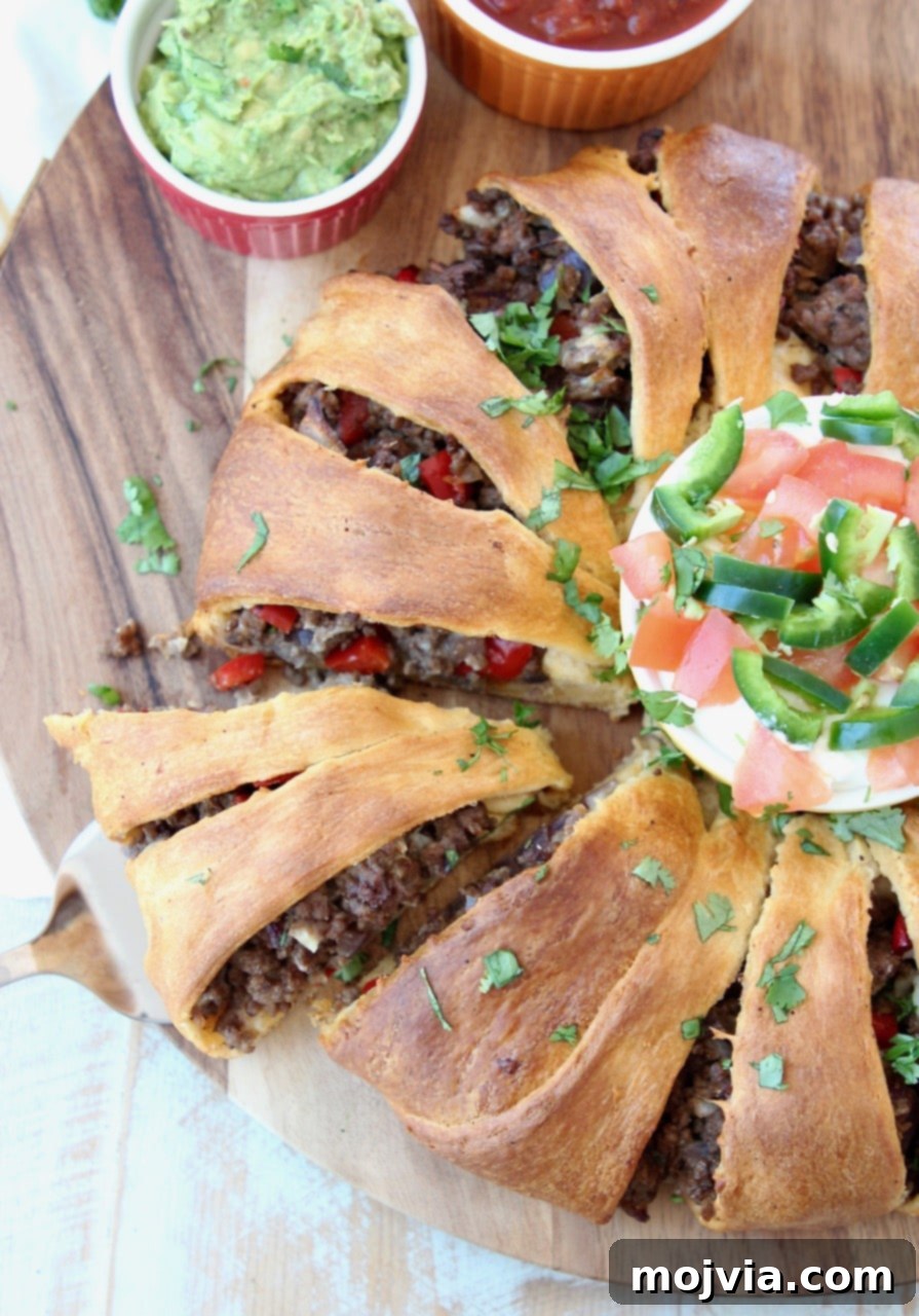 Fiesta Taco Ring 7 A fully baked crescent roll taco ring, showcasing its golden crust and delicious filling, with a single slice removed, presented on a wooden board.