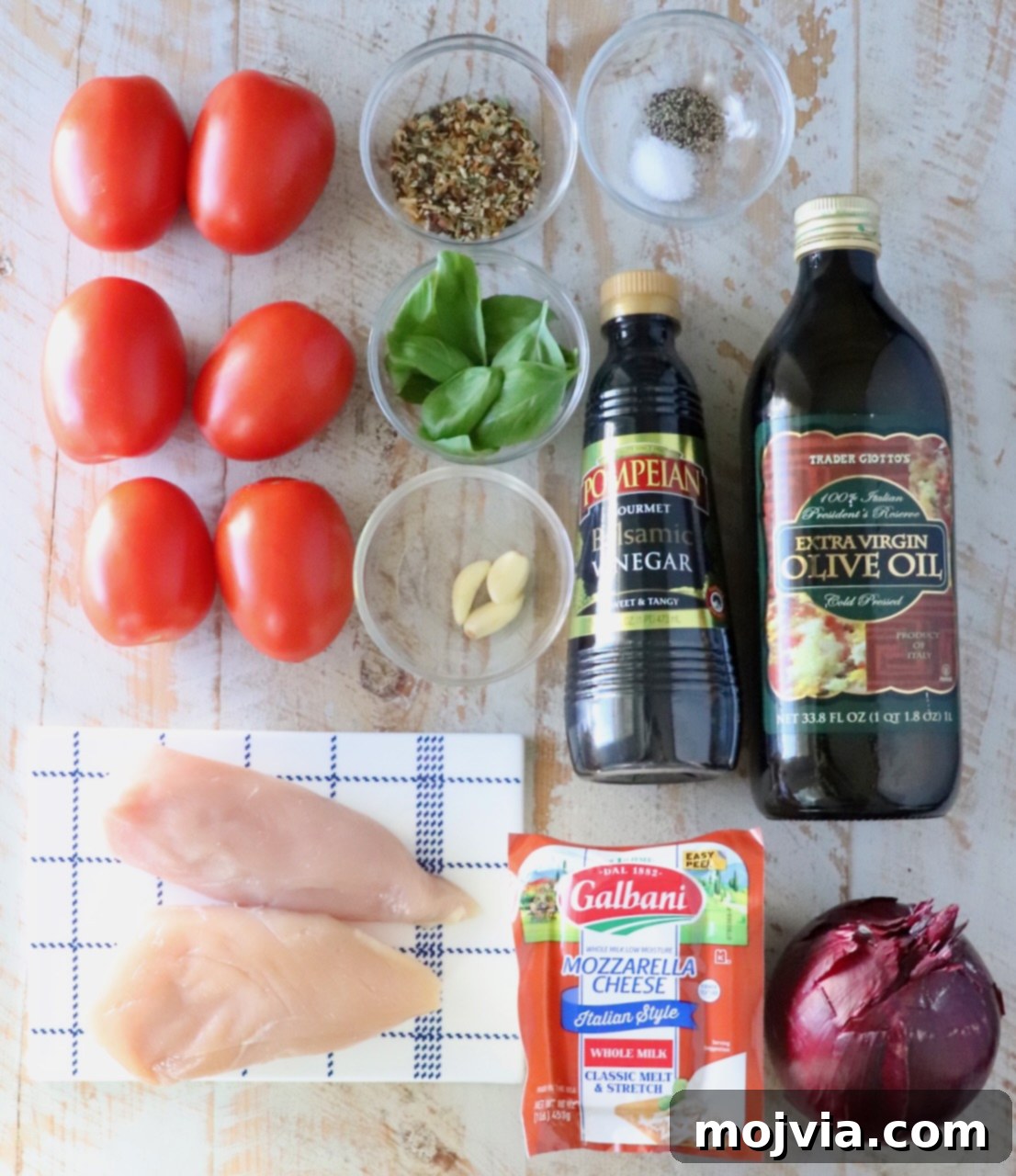 ingredients for bruschetta chicken on a white wood board