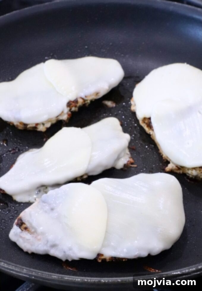 melted mozzarella cheese on top of chicken breasts in a skillet