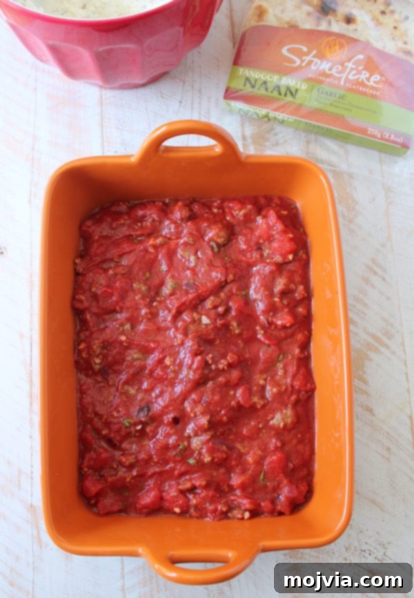 Adding a thick, rich layer of Italian sausage marinara to the Naan Lasagna assembly