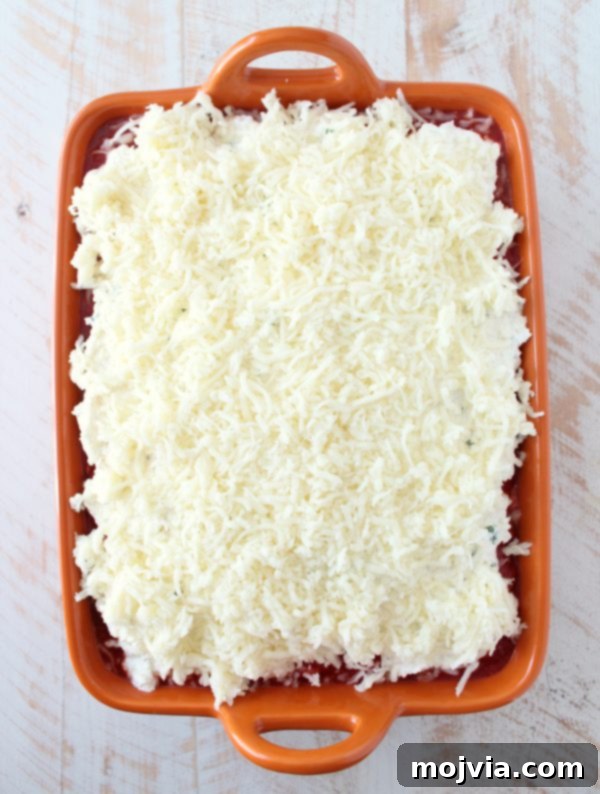 The top layer of Naan Lasagna generously covered with shredded mozzarella cheese, ready for baking