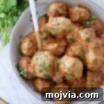 Thai Peanut Turkey Meatball Bliss 11 Thai Turkey Meatballs covered in peanut sauce in a bowl with a spoon