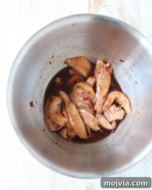 Homemade Chicken Lo Mein in Minutes 5 raw chicken strips tossed in sauce in a mixing bowl