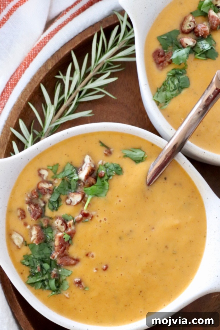 Spiced Sweet Potato Warmth 2 Two bowls of creamy sweet potato soup, garnished with fresh herbs, on a rustic table with a spoon in one bowl.