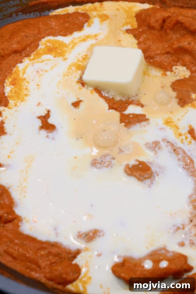 Velvet Butter Chicken 11 melted butter on top of butter chicken curry in large pan