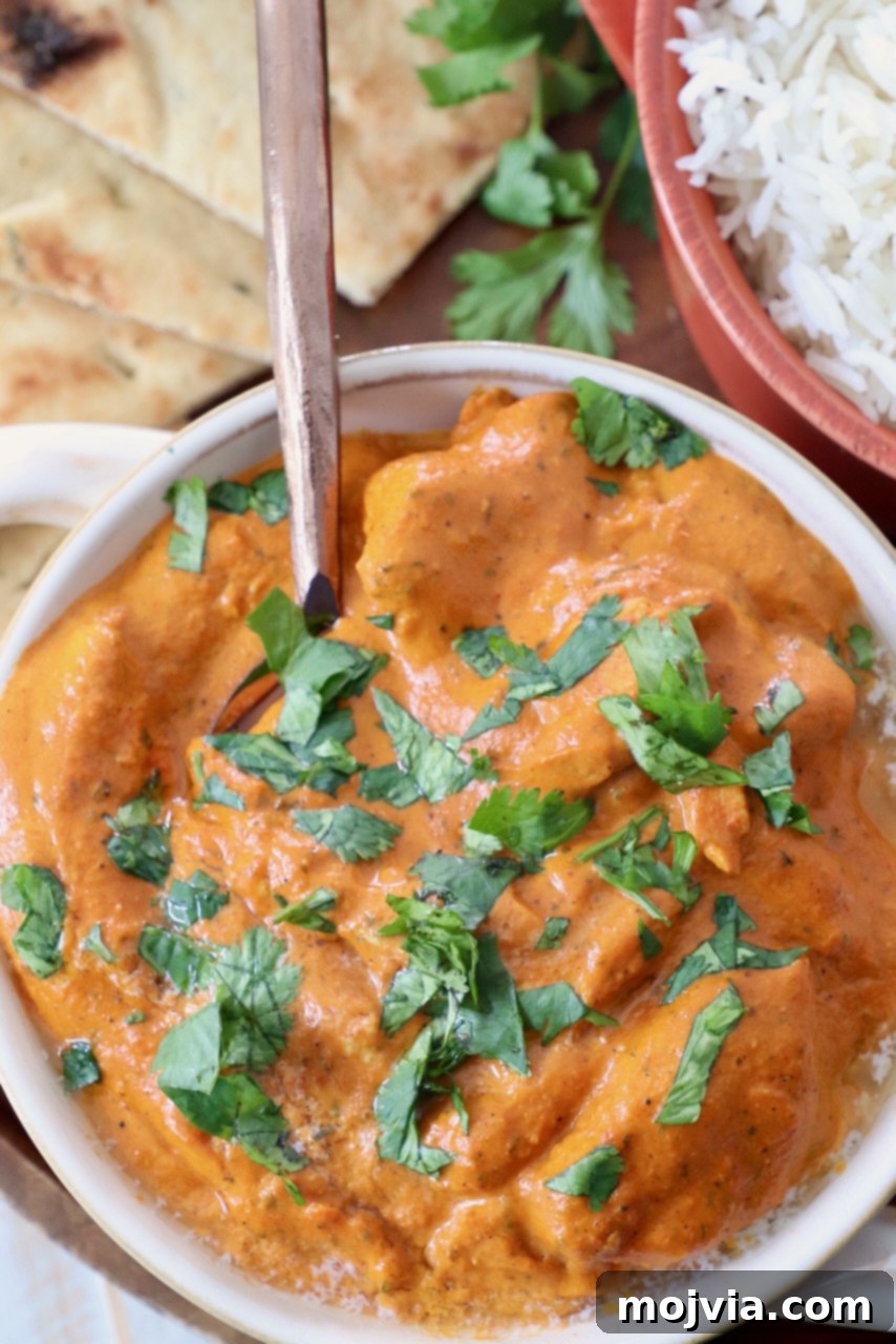 Velvet Butter Chicken 14 cooked chicken in butter curry sauce in bowl with spoon