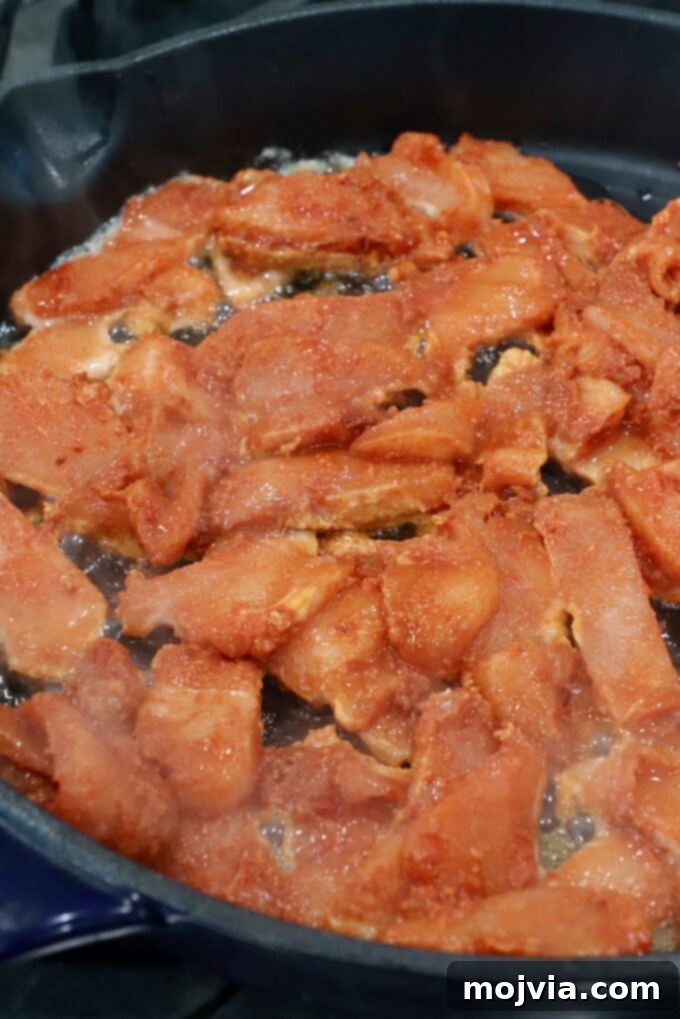 Velvet Butter Chicken 8 sliced raw chicken coated in spices, cooking in cast iron skillet