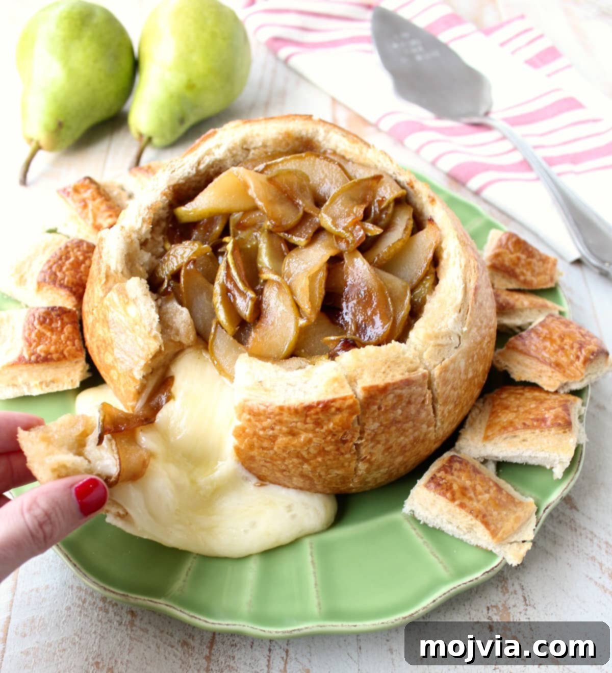 Decadent Caramelized Pear and Brie Bread Bowl 13 The finished Caramelized Pear Baked Brie Bread Bowl, garnished with fresh pear slices and toasted pieces of sourdough bread, ready to be enjoyed as a festive appetizer.