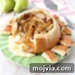 Close-up of the Baked Brie Bread Bowl with caramelized pears, ready for serving.