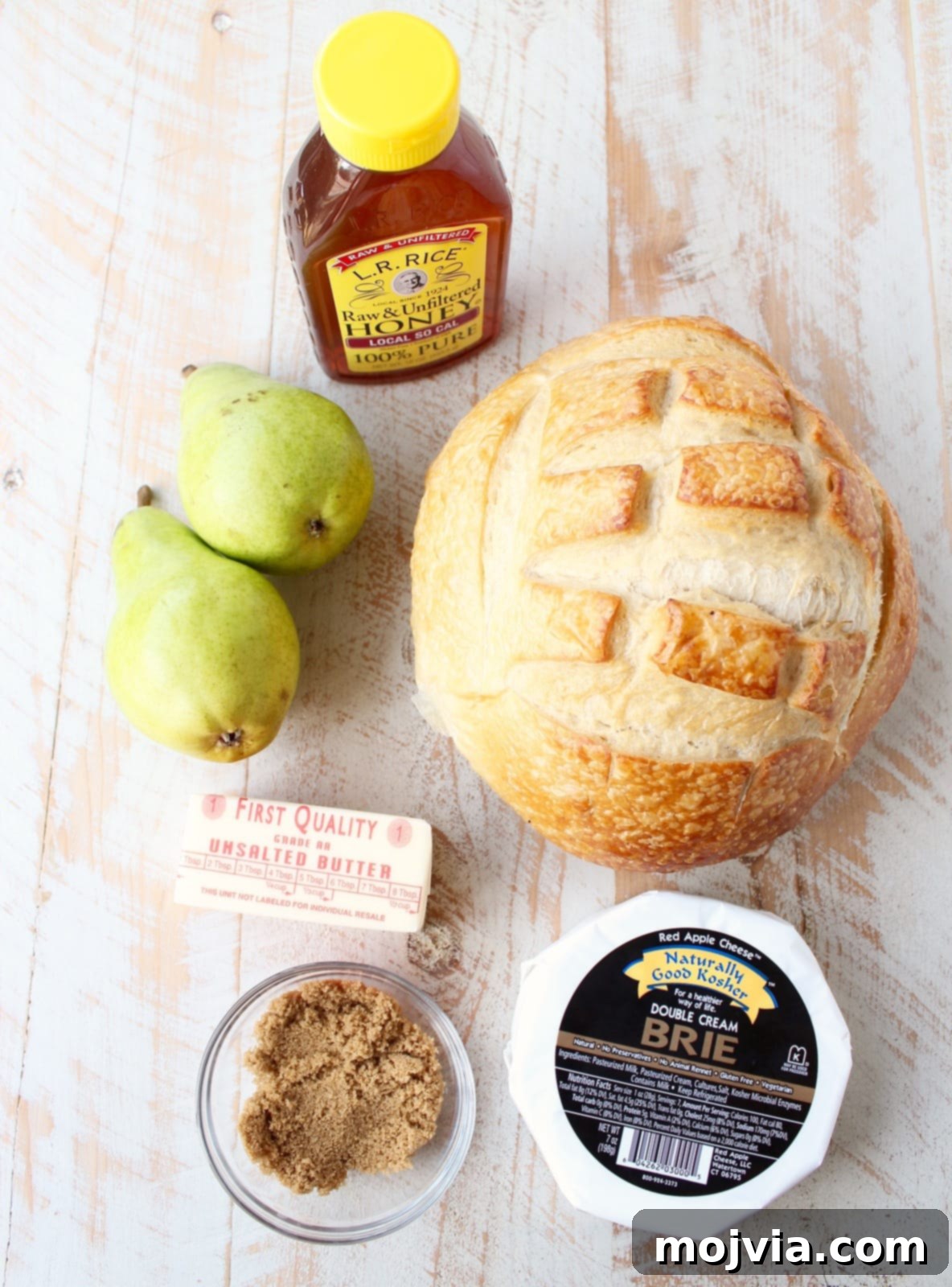 Decadent Caramelized Pear and Brie Bread Bowl 5 Essential ingredients for a Baked Brie Sourdough Bread Bowl: fresh pears, golden honey, rich butter, a wheel of brie, a rustic sourdough loaf, and brown sugar.