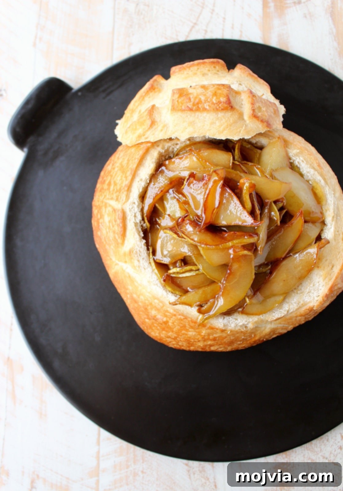 Decadent Caramelized Pear and Brie Bread Bowl 9 A prepared sourdough bread bowl on a baking sheet, filled with creamy brie, rich caramelized pears, and a glistening honey drizzle, ready for baking.