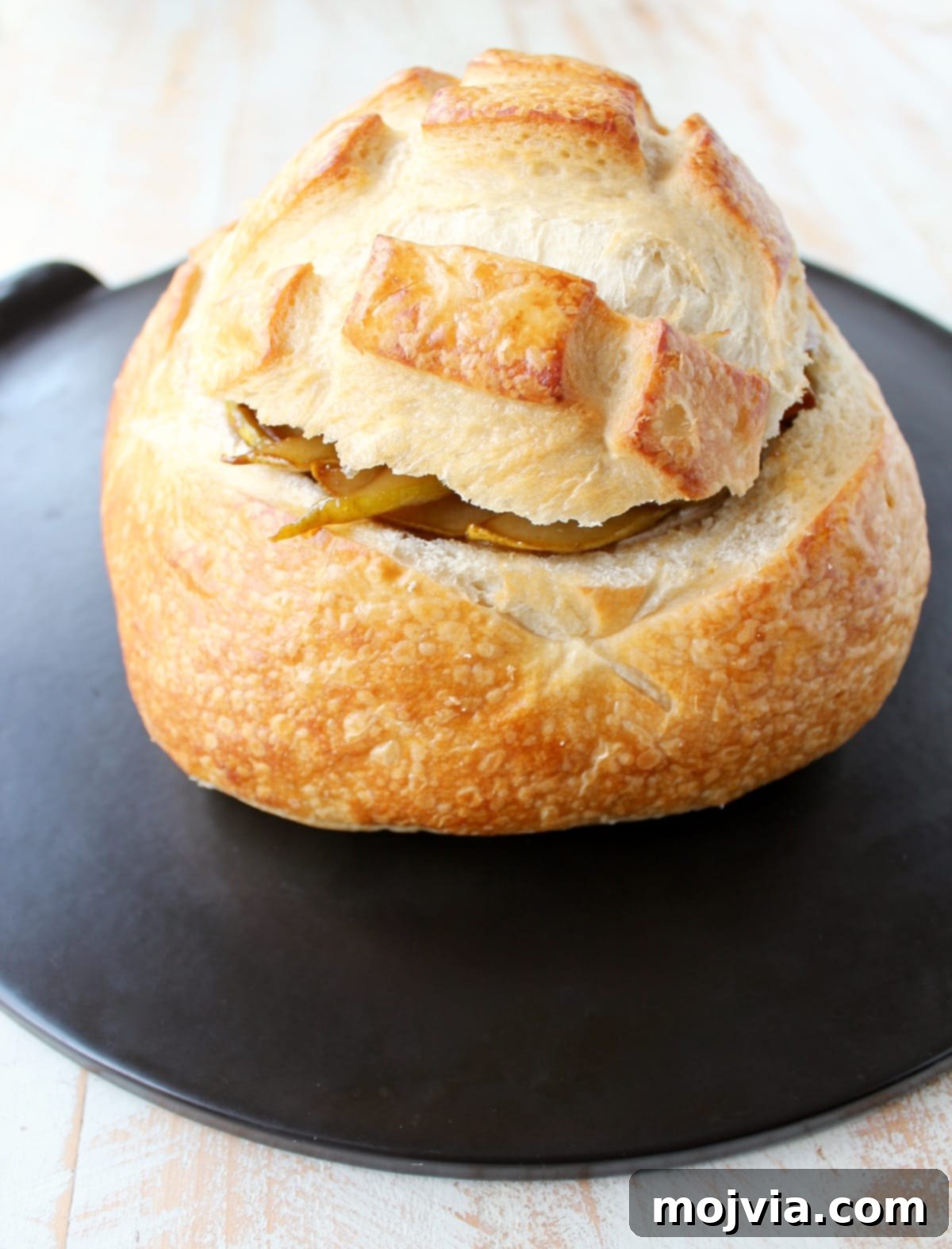 Decadent Caramelized Pear and Brie Bread Bowl 10 A sourdough bread bowl, now covered with its top slice, on a baking sheet, with brie and caramelized pears concealed inside, ready for the oven.