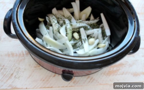 Tender Slow Cooker Chicken Ragu 4 onion, garlic cloves and fresh rosemary in the bottom of a slow cooker.