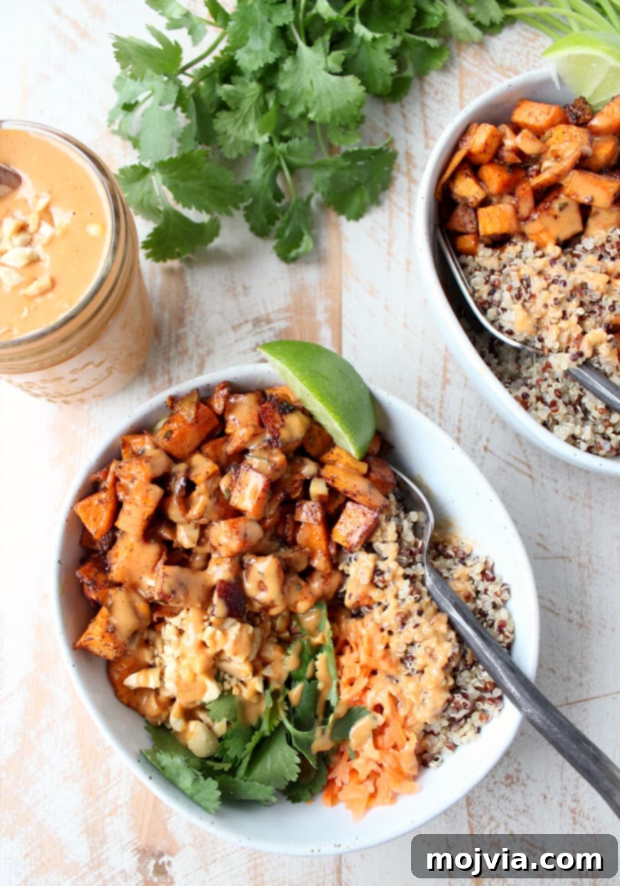 Vibrant Thai Peanut Sweet Potato Bowl 3 An overhead view showcasing two delightful bowls filled with roasted sweet potatoes, fluffy quinoa, and vibrant shredded carrots, all generously drizzled with rich Thai peanut sauce.
