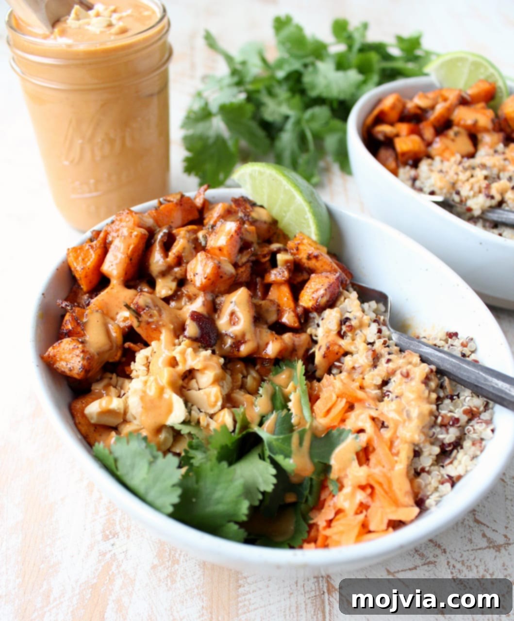 Vibrant Thai Peanut Sweet Potato Bowl 5 A close-up shot of a single serving of roasted diced sweet potatoes and fluffy quinoa, elegantly arranged in a bowl and topped with a generous swirl of Thai peanut sauce.